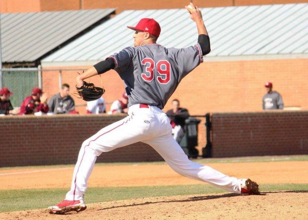 Alumni Story Joe Kuzia photo3 St. Johns Joe Kuzia throws a baseball to his left while on the pitcher's mound. He's dressed in a gray and red jersey.